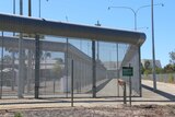 Wire fence outside Perth's Hakea Prison with prison building visible in background