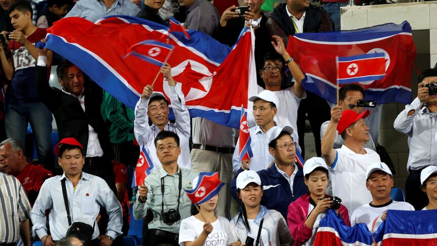 Fans hold up the North Korean flags before a match.