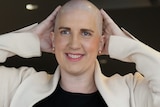 A woman with a shaved head smiles