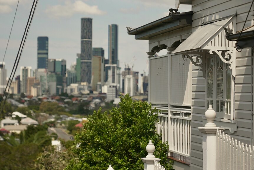A side-view of a typical Queenslander house, with Brisbane city's skyline in the distance.
