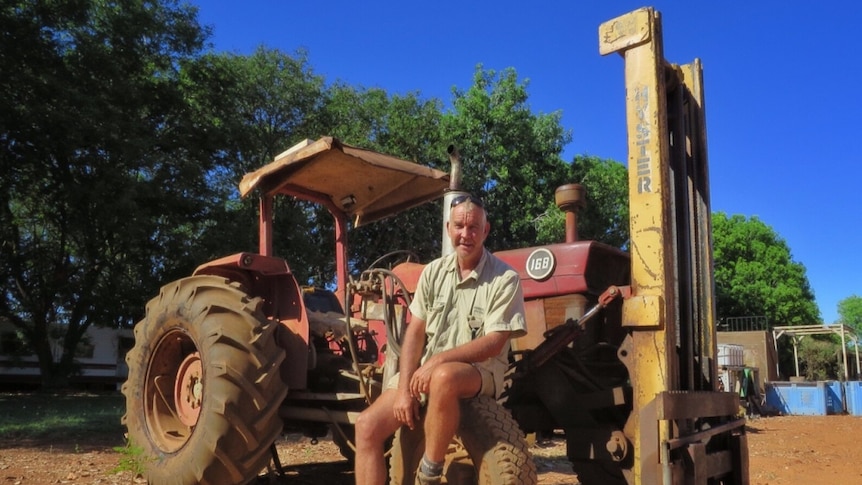 Farmer Lachlan Dobson sits on the wheel of a vintage tractor