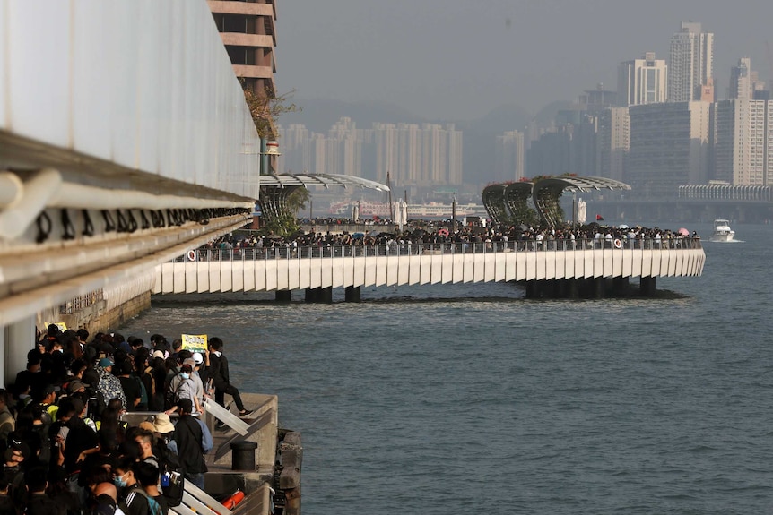 Looking below to jetties on Hong Kong's waterfront, you view large crowds of protesters filling all available space.