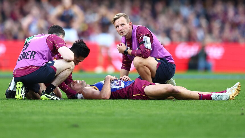 A Brisbane Lions AFL player is attended to after being injured.