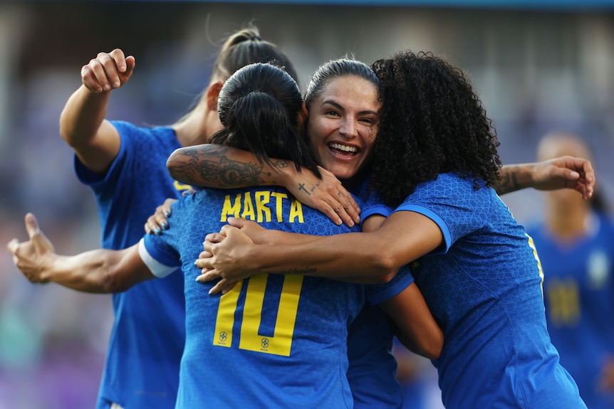 Four Brazilian players embrace as they celebrate a goal in a friendly against Japan.