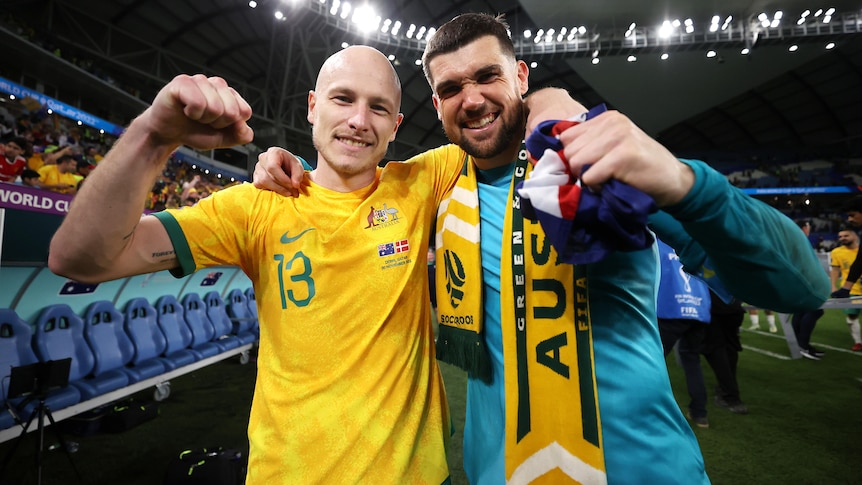 Two Socceroos players pump their fists as they celebrate beating Denmark at the FIFA World Cup.