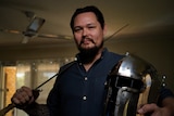 Man poses with sword and helmet