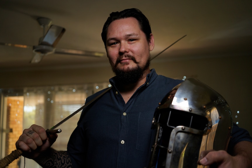 Man poses with sword and helmet