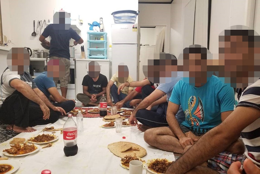 Pixellated image of a group of asylum seekers eating food in a kitchen at a detention centre on Nauru.