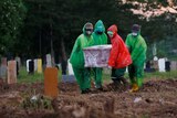 Jakarta municipality workers carry a coffin of a coronavirus victim to be buried.