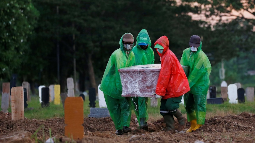 Jakarta municipality workers carry a coffin of a coronavirus victim to be buried.