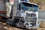 A semi-trailer rests roadside, front crushed.