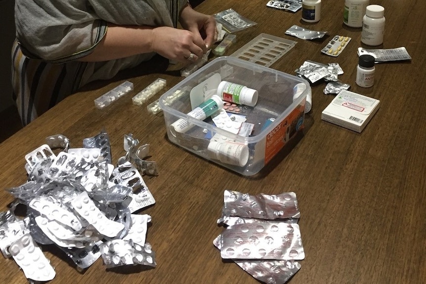 A woman's hands with bottle and packets of medication.