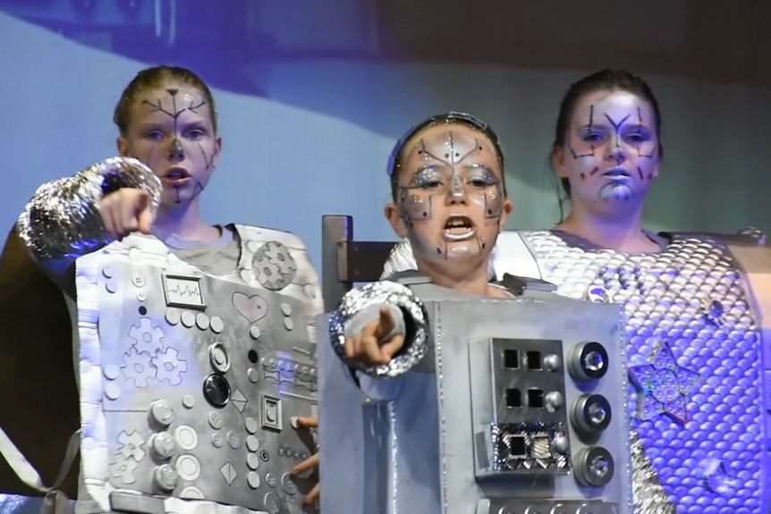 three performers sressed in silver costumes