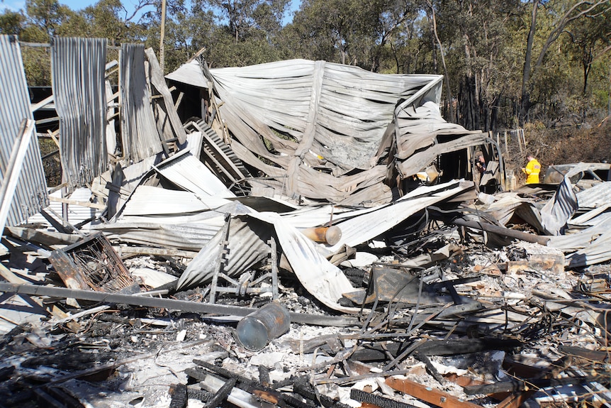 Charred, twisted corrugated metal sheeting and rubble at the site of a house razed by bushfire