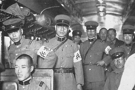 Uniformed Japanese military members face the camera on a train