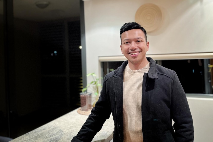 A man smiling to camera in his office