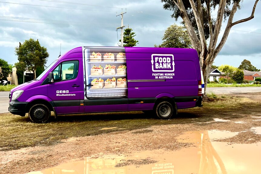 A purple van off road, near puddles, in a regional community