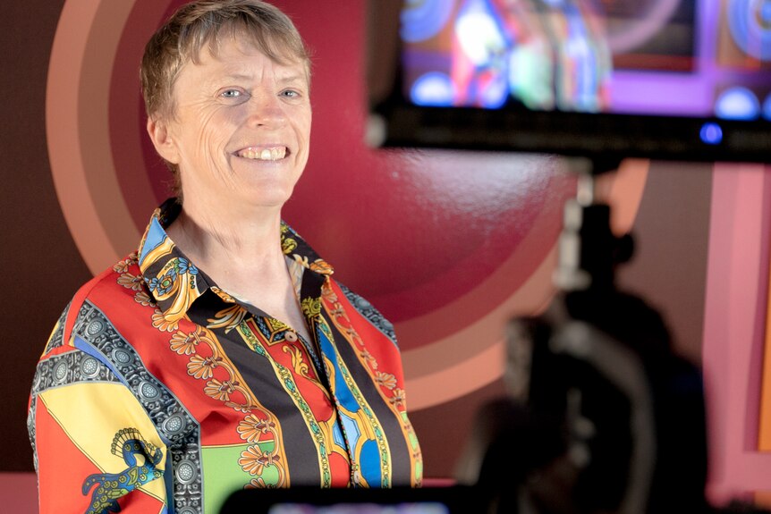 a person in a colourful shirt smiles at the camera