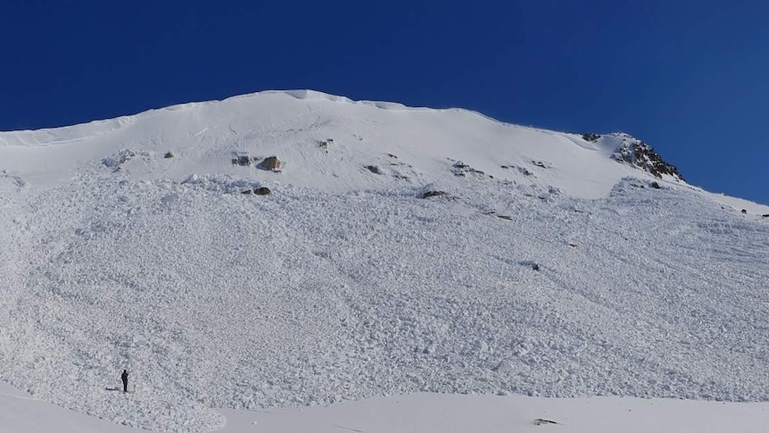 Two men walk in the remainder of an avalanche.