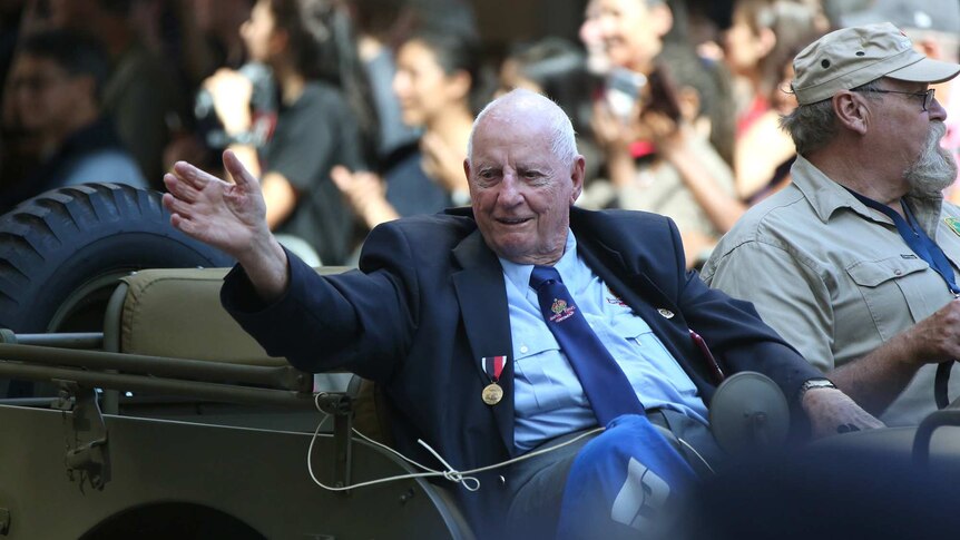 A veteran waves to the crowd from a military jeep in the Brisbane Anzac Day march on April 25, 2018.