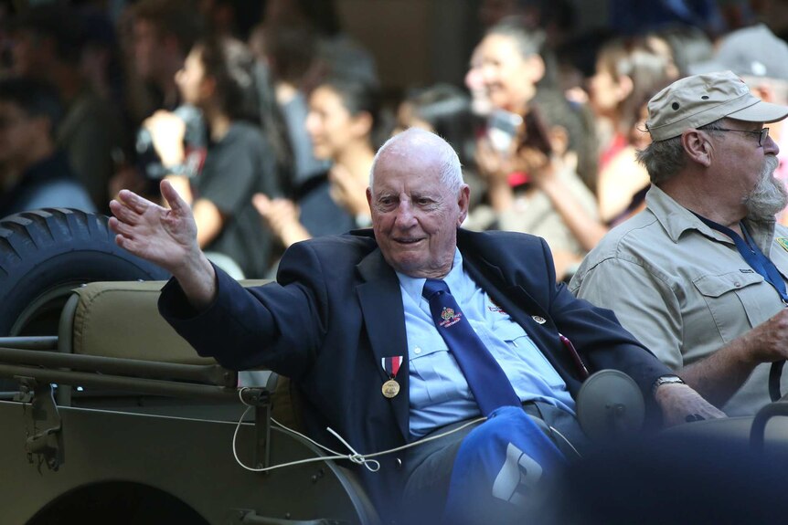 A veteran waves to the crowd from a military jeep in the Brisbane Anzac Day march on April 25, 2018.