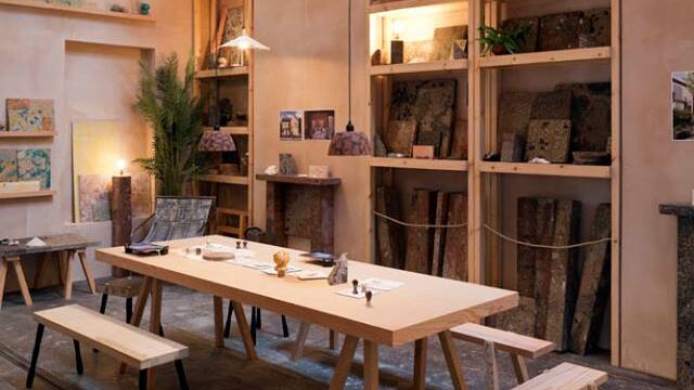Assemble's workshop, featuring a long wooden table and low-hanging lights.