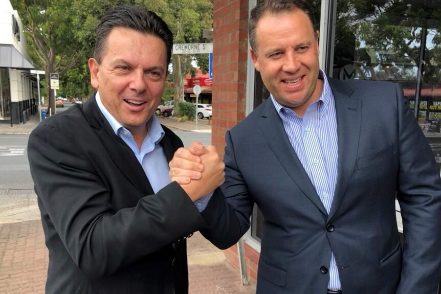 Nick Xenophon and Anthony Olivier clasp hands.