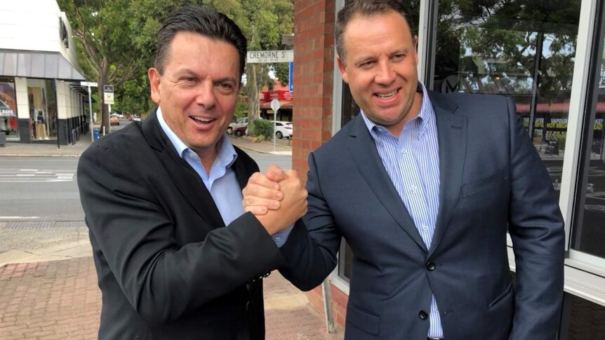 Nick Xenophon and Anthony Olivier clasp hands.