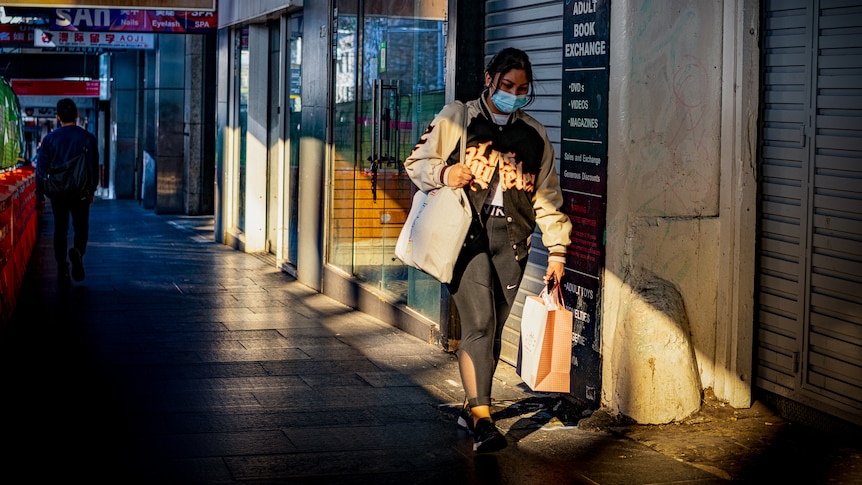 a woman in a mask shopping on a sydney street