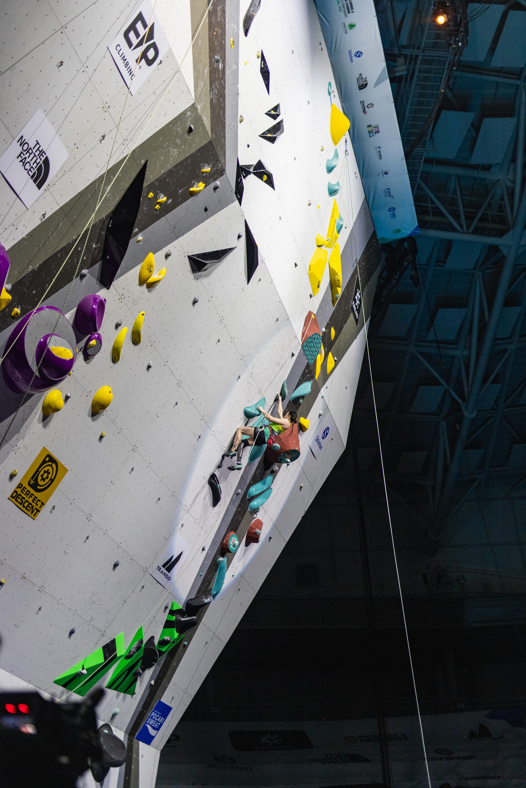 Uma imagem ampla da parede de chumbo nos campeonatos mundiais de paraescalada. A australiana Sarah Larcombe está escalando.