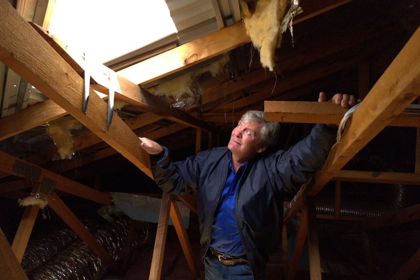 A man looks at a hole in a roof.