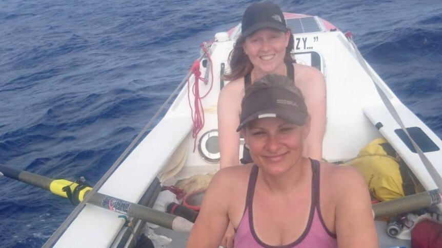 Two women rowing in ocean.