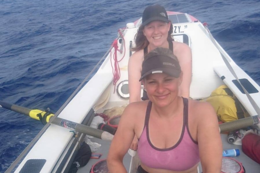 Two women rowing in ocean.
