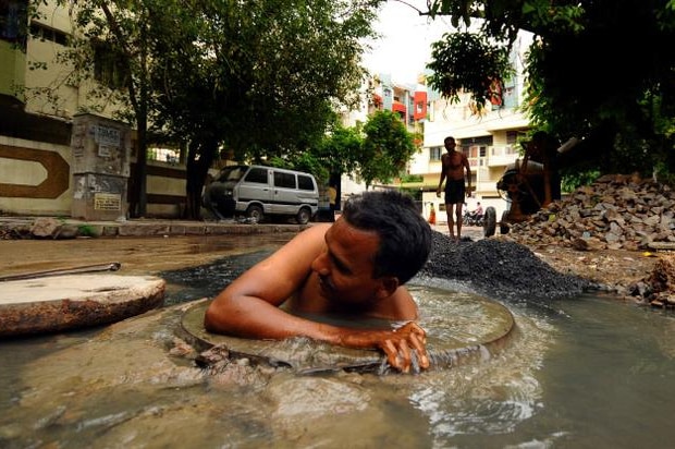 An Indian dalit man shoulder deep inside a sewer without this shirt on.