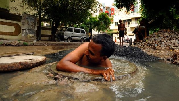 An Indian dalit man shoulder deep inside a sewer without this shirt on.