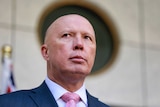 Peter Dutton in a suit looking to left of camera, framed by a round window.