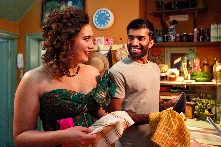 Rose Matafeo in a lavish gown dries the dishes in her cluttered kitchen with Nikesh Patel in Starstruck