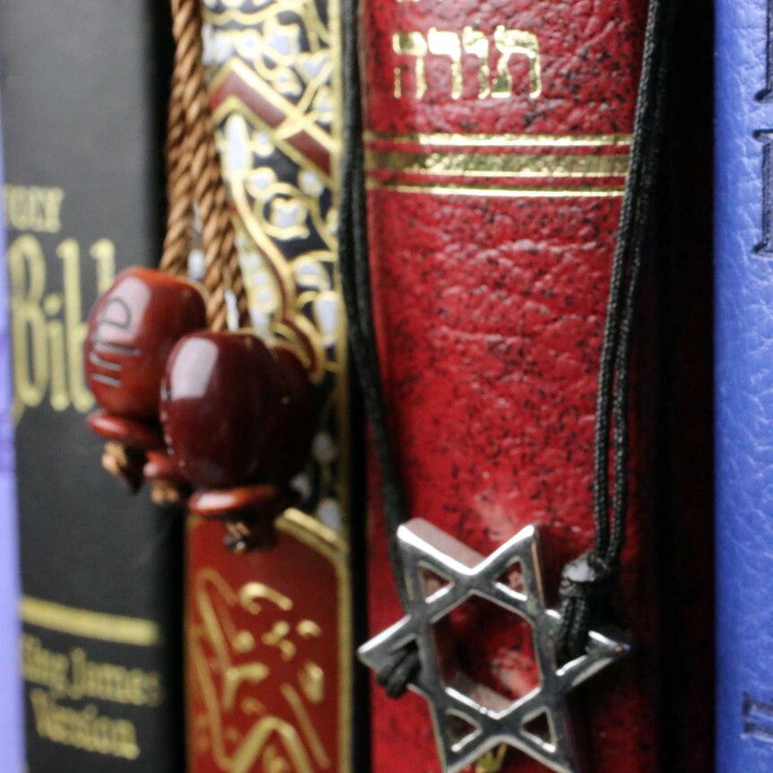 Christian Crucifix, Islamic symbol and Jewish star of David with Bible, Quran and Torah