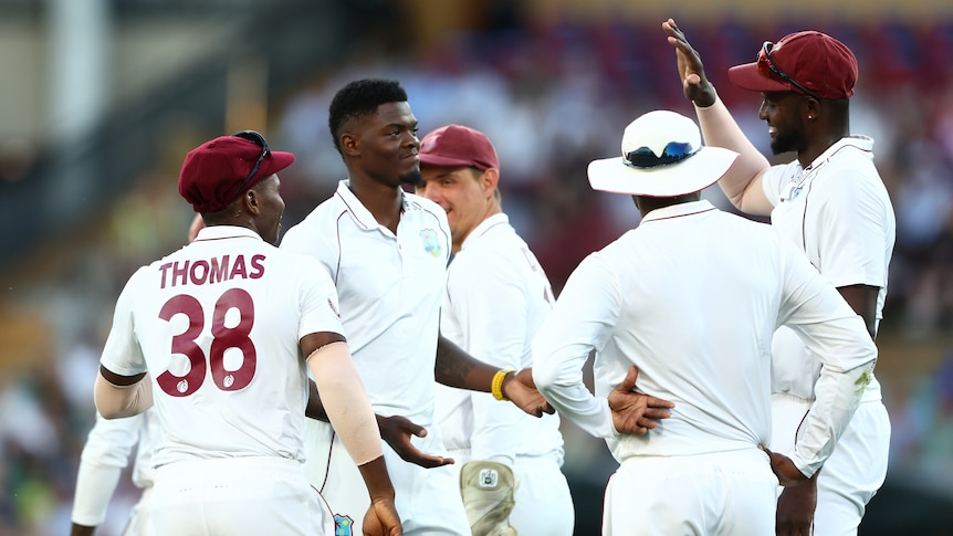 West Indies players high five a bowler who has just taken a Test wicket.