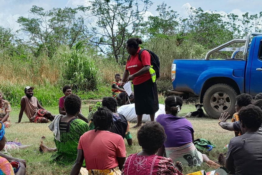 A ni-Vanuatu woman teaching other women outisde on the grass