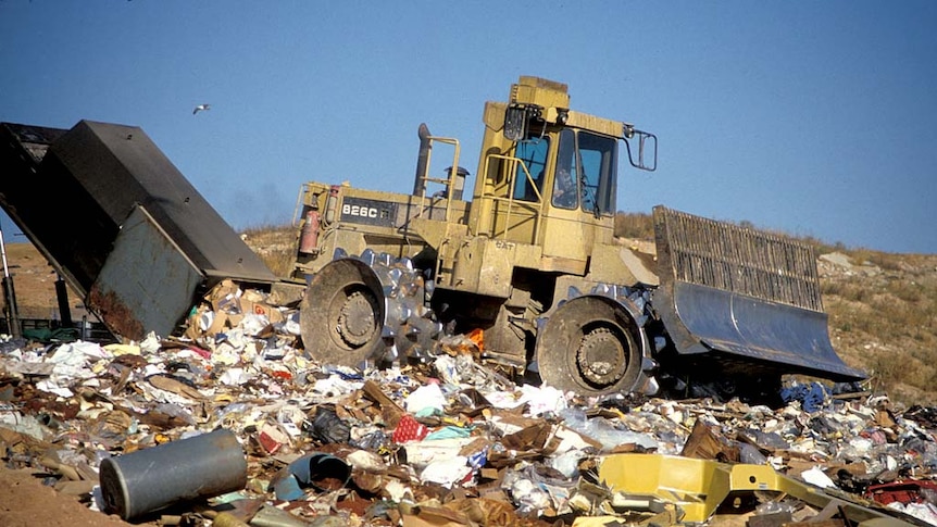 A bulldozer driving across rubbish.