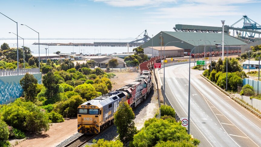 A landscape showing the Esperance port, ocean and a train full of iron ore rolling past