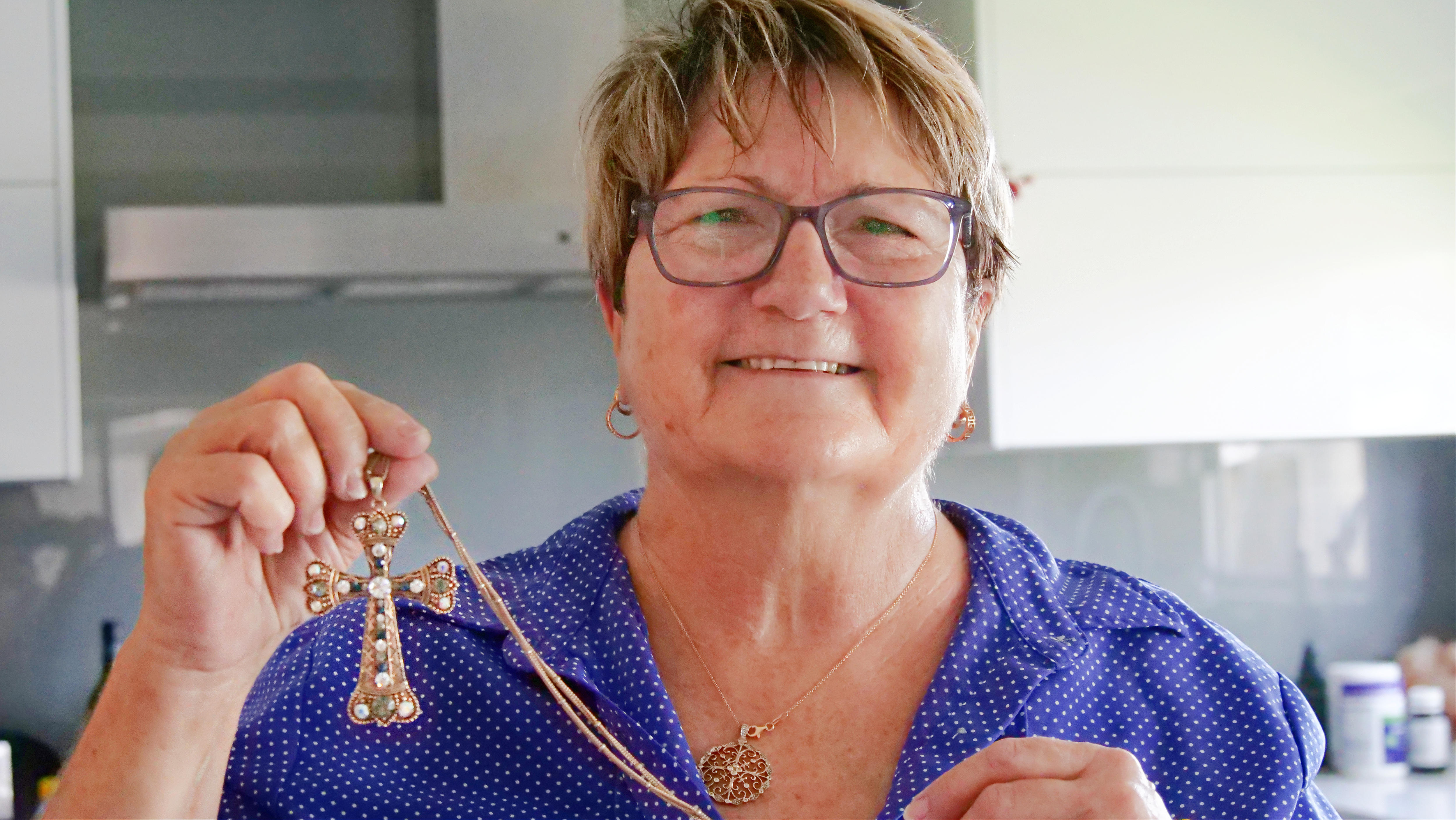 Crocky Murphy proudly holding her gold cross with blue and grey jewels, in the Cowboys colours