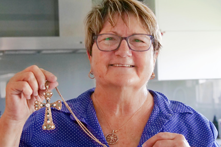 Crocky Murphy proudly holding her gold cross with blue and grey jewels, in the Cowboys colours