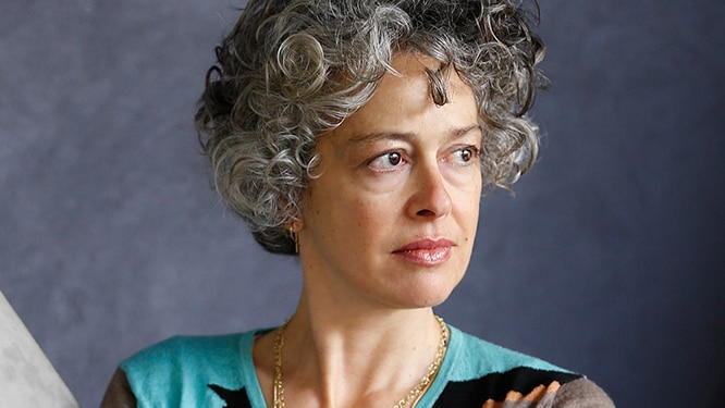 Portrait of dancer and choreographer Shelley Lisaca. She has grey curly hair and is crossing her arms.