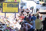 People collecting flowers and teddy bears outside a primary school.