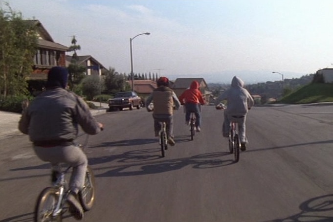A screenshot shows kids on BMX bikes riding down a suburban street. 
