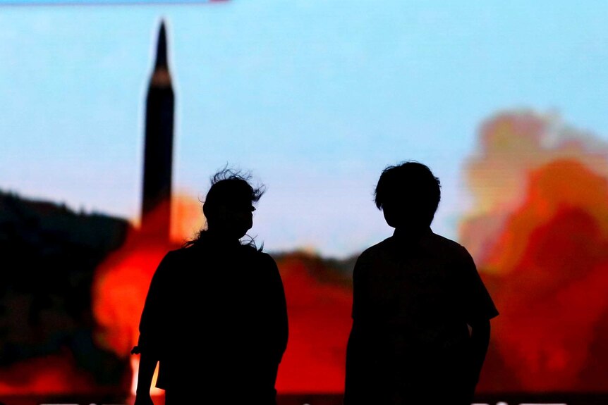 People in Tokyo walk in front of a monitor showing news of North Korea's fresh missile threat.