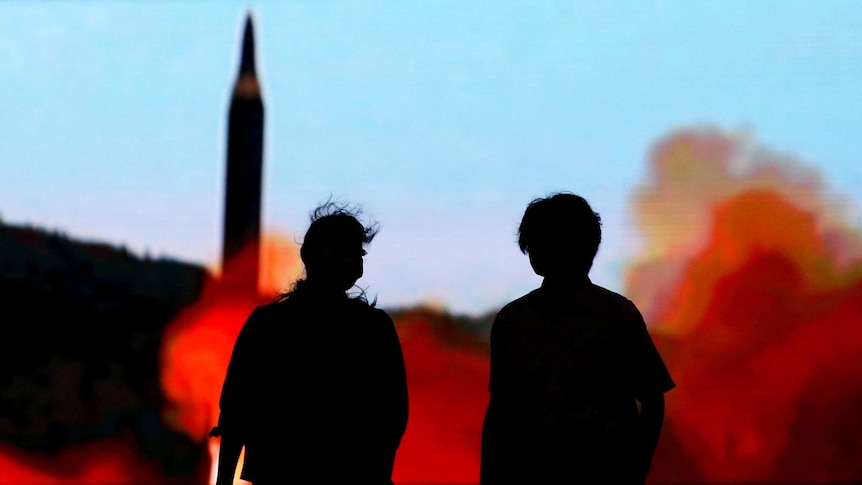 People in Tokyo walk in front of a monitor showing news of North Korea's fresh missile threat.