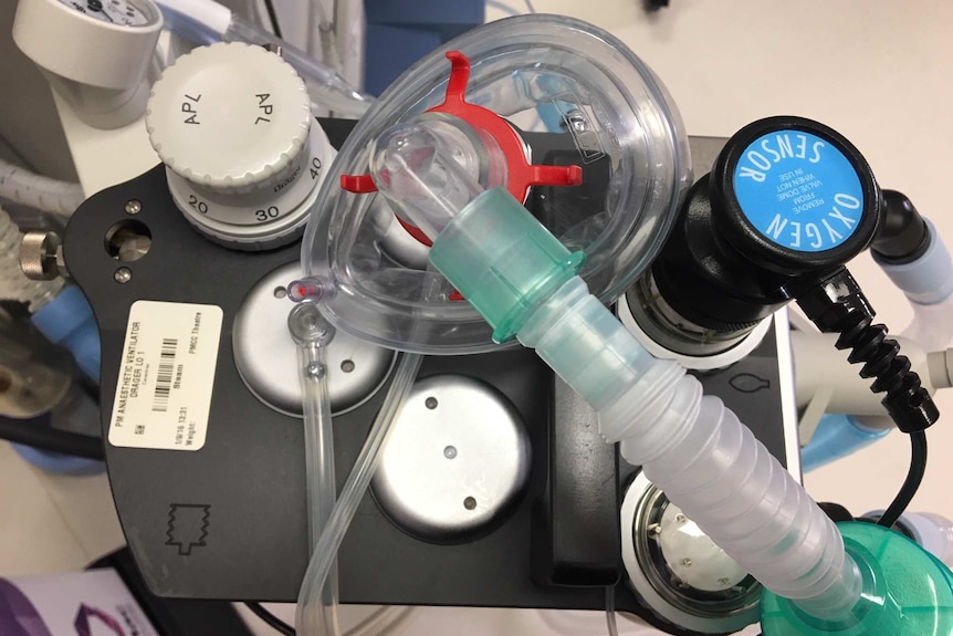 A gas mask sits on anaesthetic equipment with dials and a screen reading 'oxygen sensor'.